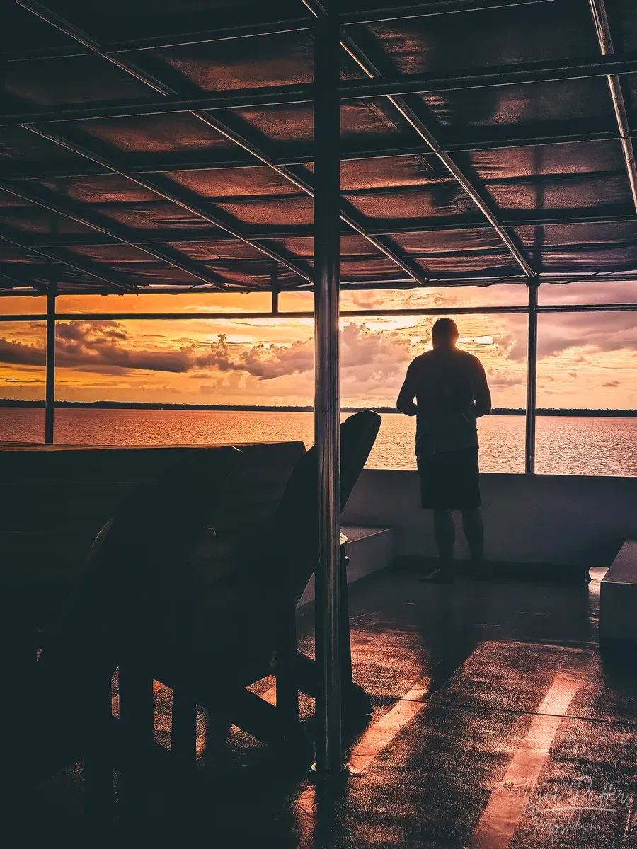 Diving Raja Ampat Indonesia Travel Photos 06 by Lynn Peiffer A man at the side of a boat gazes at an orange sunset over the sea in Raja Ampat, Indonesia.