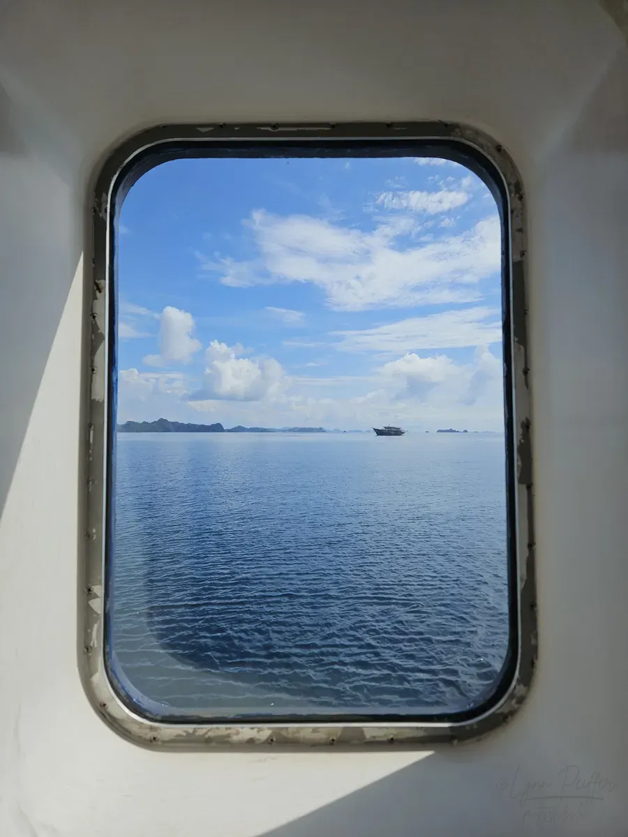Diving Raja Ampat Indonesia Travel Photos 09 by Lynn Peiffer A porthole reveals blue sea, small islands and a sky dotted with clouds in Raja Ampat, Indonesia.