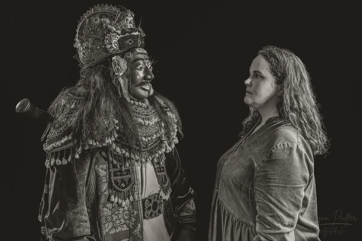 A portrait of Lynn Peiffer facing a Balinese man dressed in an elaborate Topeng Keras costume.
