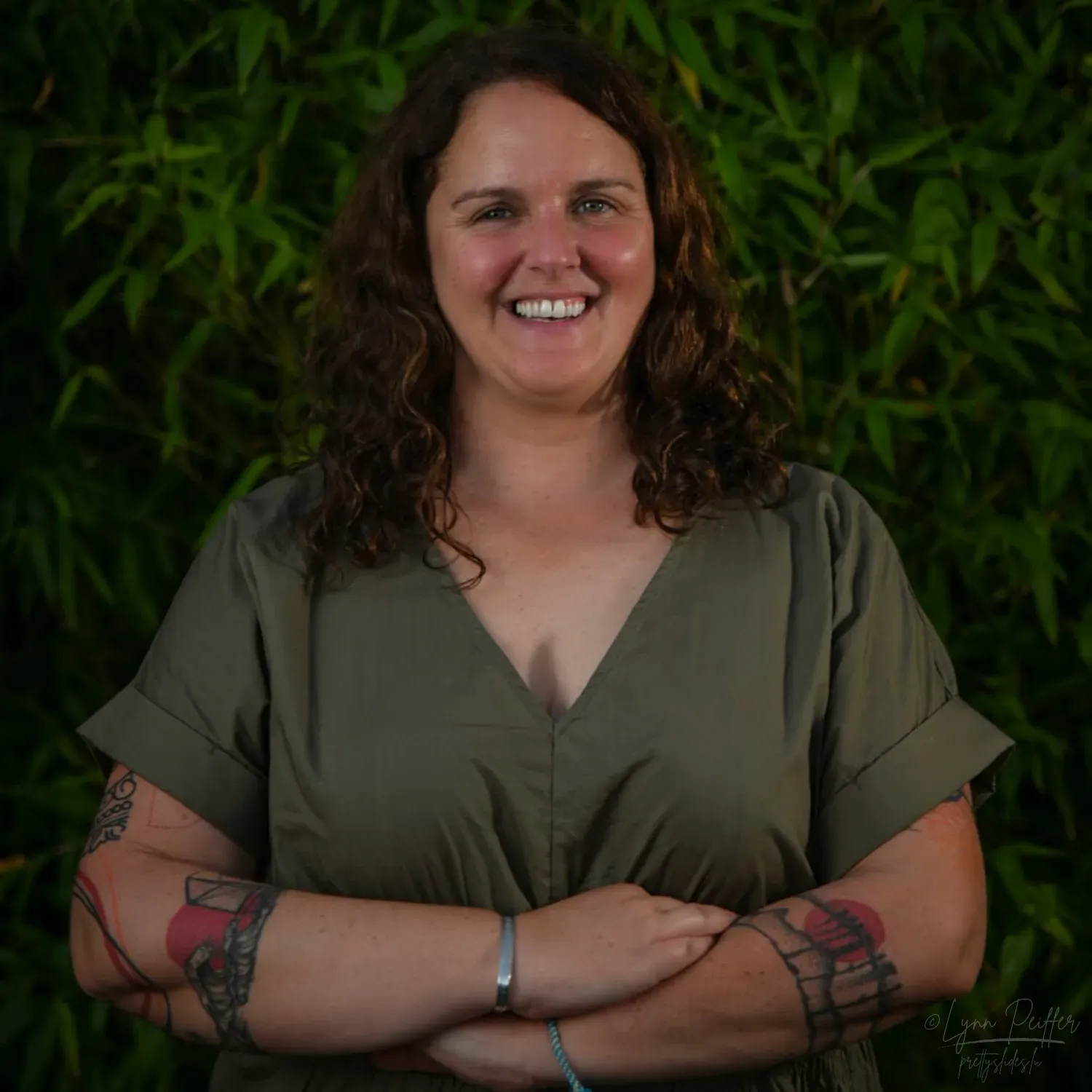 Portrait of Luxembourg photographer Lynn Peiffer, smiling at the camera with arms crossed in front of her.