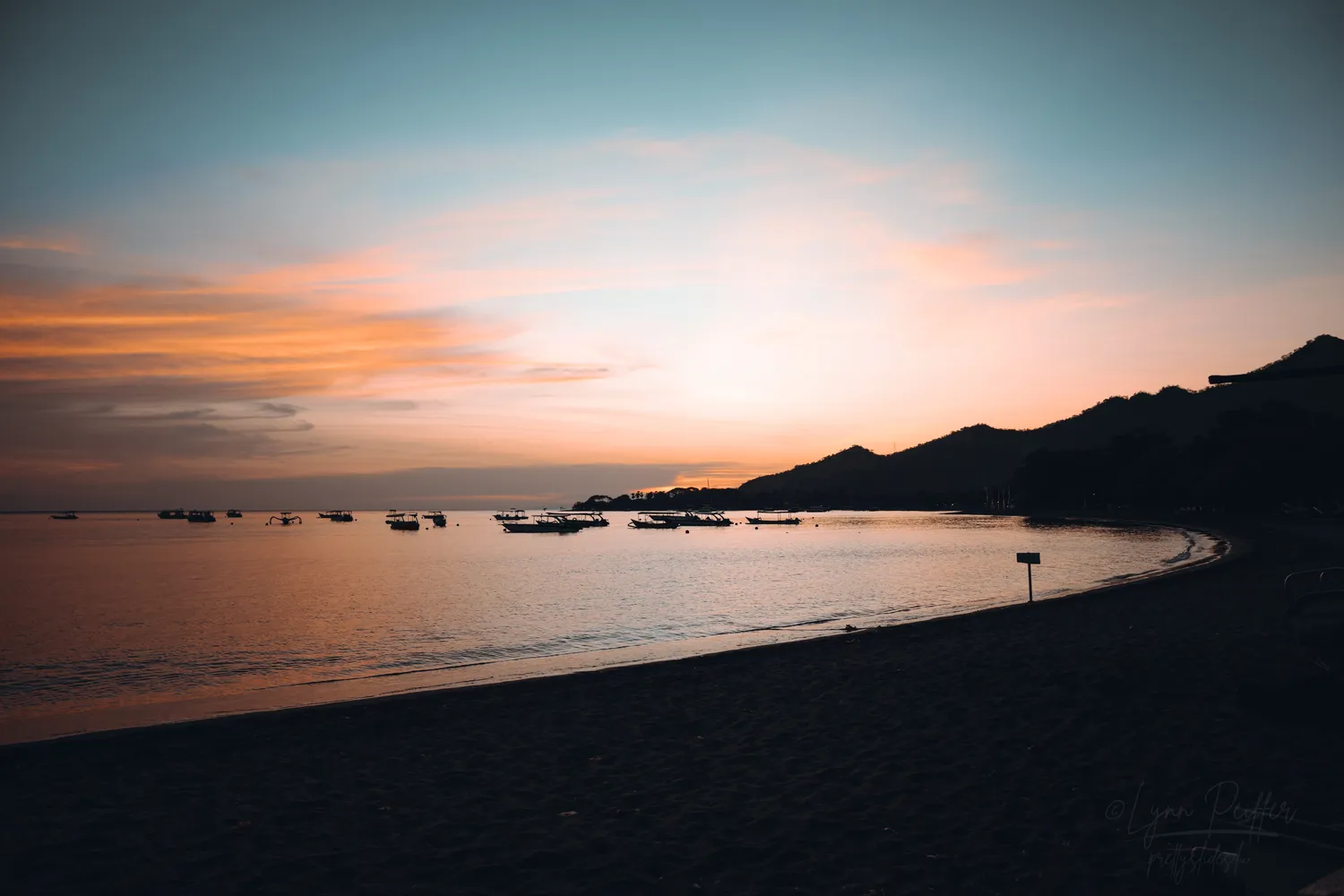 Places of Indonesia Landscape Travel Photos 13 by Lynn Peiffer Pink clouds during sunrise over boats floating in Pemuteran Bay in Indonesia.